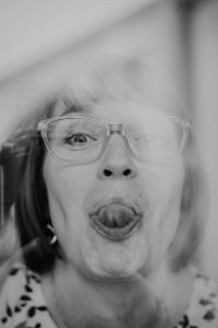 Karoline Krey, Coachin bei marvelousme, zeigt humorvoll ihre verspielte Seite mit einem lustigen Gesichtsausdruck hinter Glas – authentisch, nahbar und menschlich