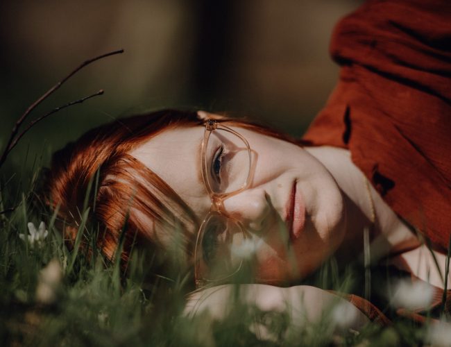 Karoline Krey, Coachin für persönliche Transformation bei marvelousme, liegt entspannt im Gras und blickt nachdenklich in die Kamera